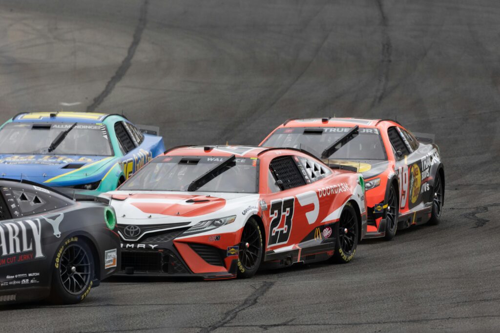Dynamic image of stock cars racing closely on a track during a motorsport event.
